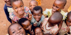 A group of happy children playing outdoors in Kigali, Rwanda, capturing joyful expressions and vibrant smiles.