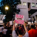 A vibrant Black Lives Matter protest with signs and a diverse crowd in an urban setting.