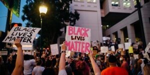 A vibrant Black Lives Matter protest with signs and a diverse crowd in an urban setting.